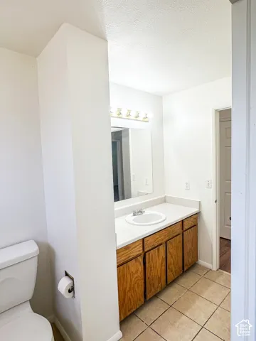 Recessed lighting fixture, light wood-finish cabinetry, white countertop, white sink basin, and tile flooring
