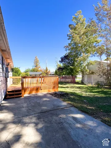 Wooden deck with railings, steps, and concrete patio