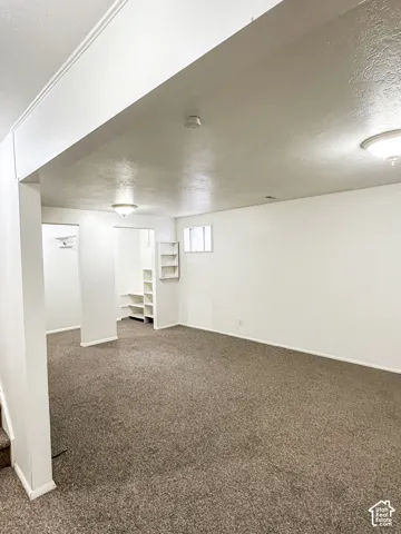 Expansive carpeted area with recessed lighting, built-in shelving, and multiple windows