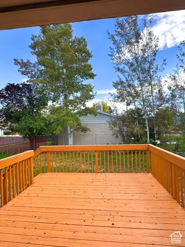 Spacious wood deck with perimeter railing and mature trees