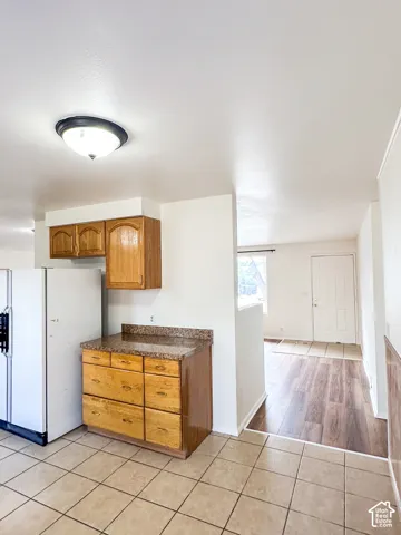 Kitchen area featuring tile flooring, wooden cabinetry, and a speckled countertop
