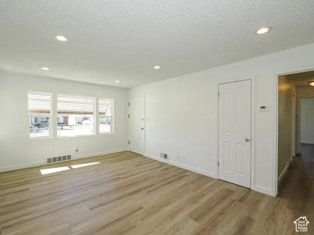 Recessed lighting illuminates the space, featuring wood-finish flooring and multiple windows