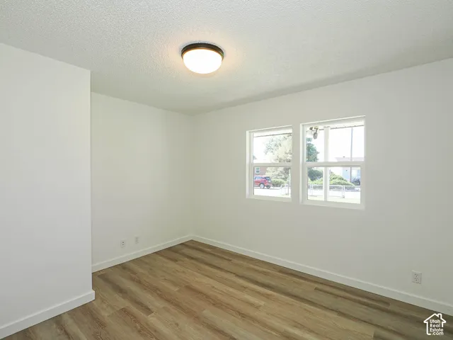 Twin windows, wood-finish flooring, white walls, and a flush-mount ceiling light