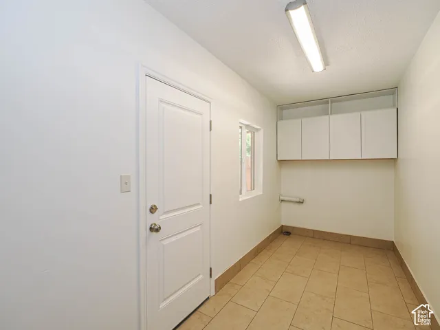 White walls, tiled flooring, built-in upper cabinetry, and a window