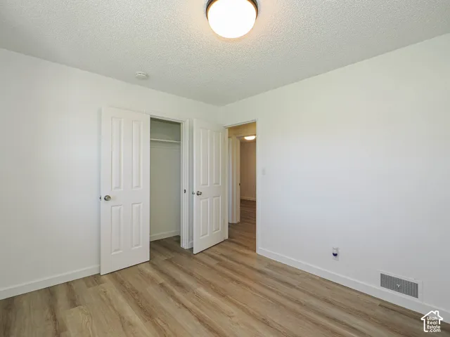 Wood-finish flooring, white paneled doors, ceiling-mounted light fixture, and a built-in closet with hanging rod