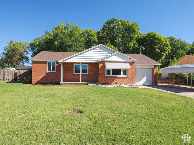 Brick exterior with white siding accents and a covered carport, featuring a single-car garage and a fenced yard