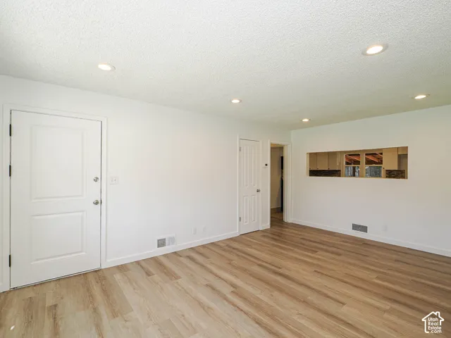 Recessed lighting, wood-finish flooring, white paneled doors, and a pass-through window