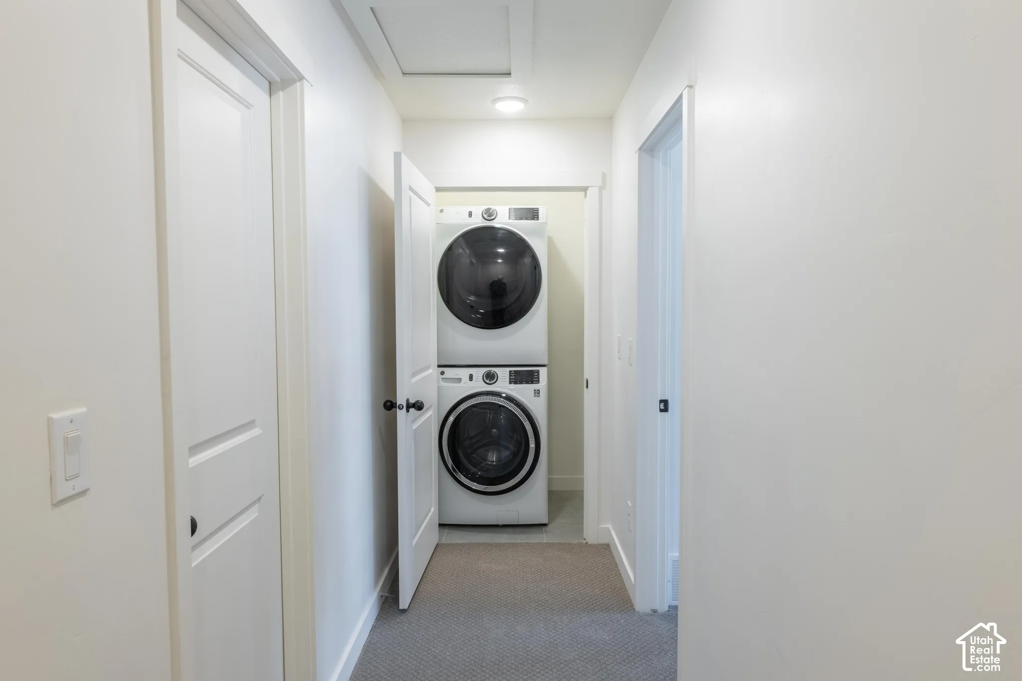 Hallway laundry closet featuring a stacked washer and dryer
