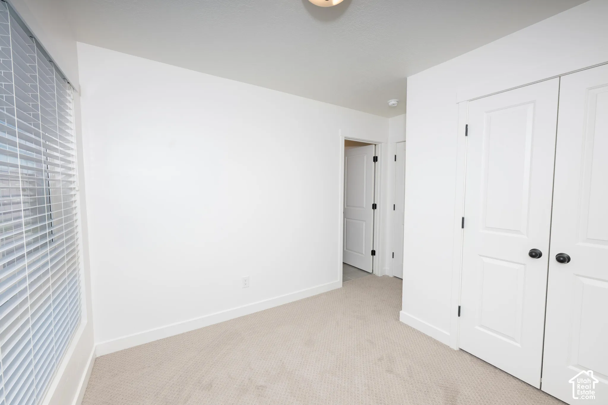 Plush carpeting, window with horizontal blinds, built-in closet with double doors, and white paneled interior doors