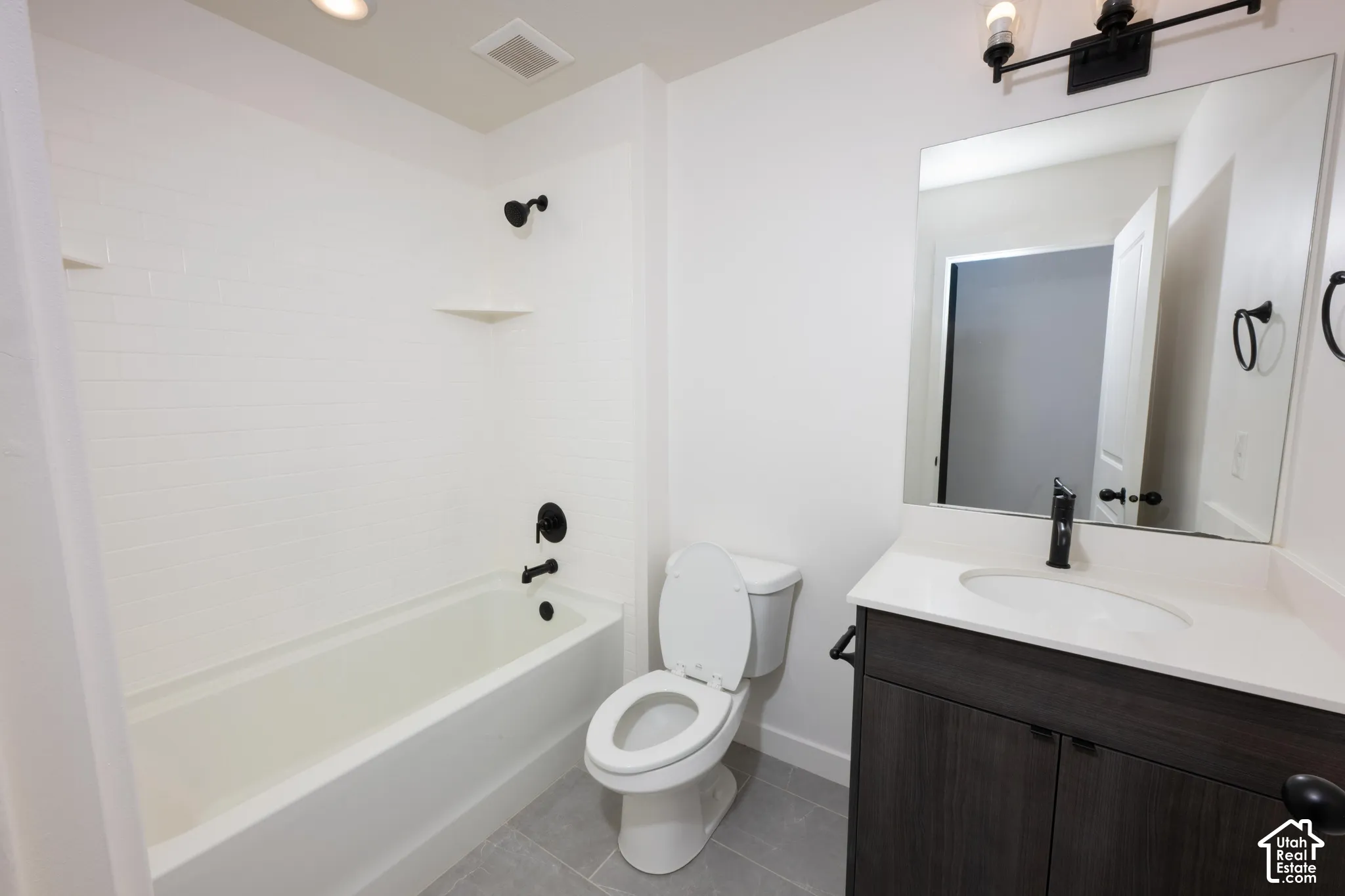 White subway tile tub surround, dark wood-finish vanity with white countertop, integrated sink, matte black faucet, and rectangular mirror