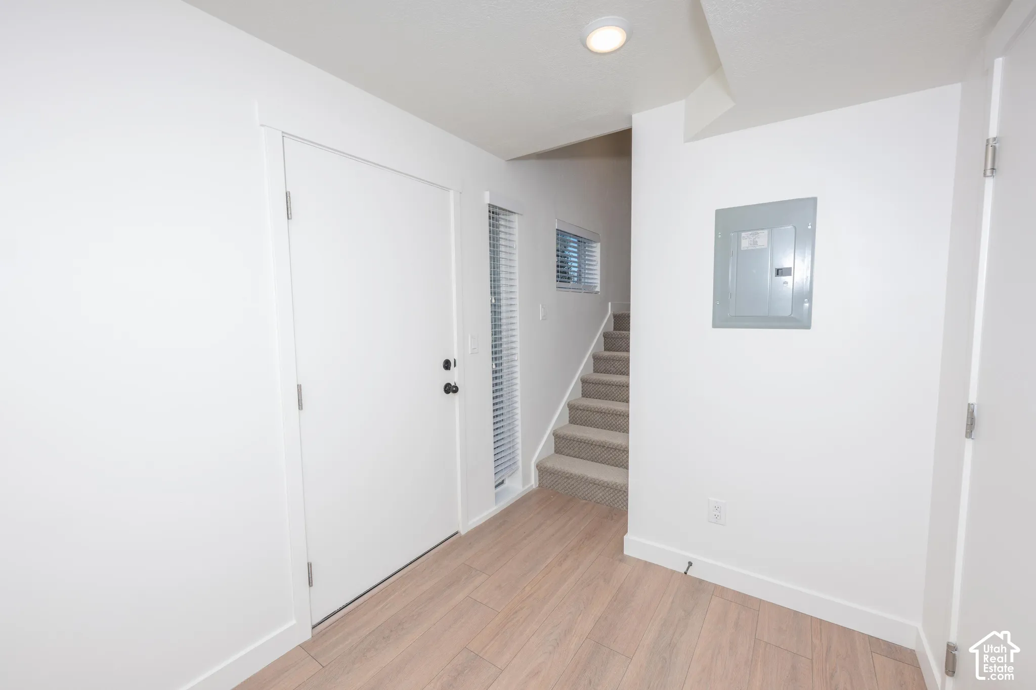 Wood-finish flooring, white walls, and a carpeted staircase