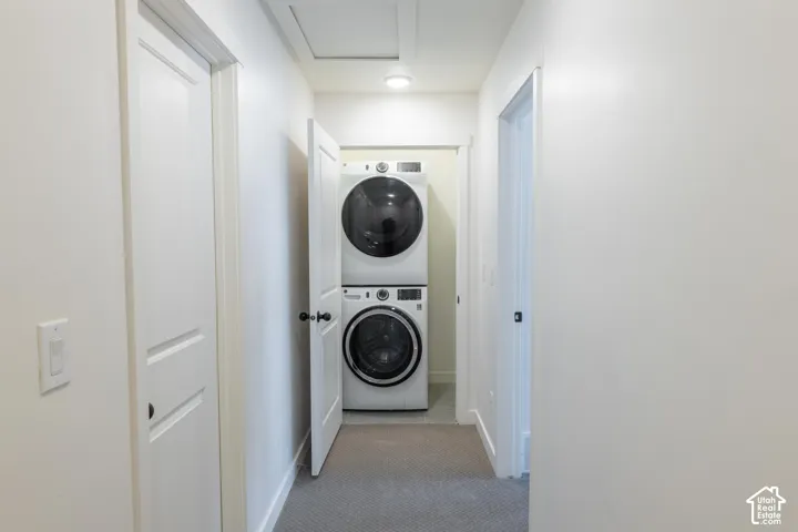 Hallway laundry closet featuring a stacked washer and dryer