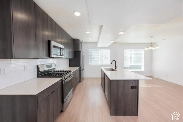 Modern kitchen featuring dark wood-finish cabinetry, stainless steel appliances, white subway tile backsplash, and light-toned countertops