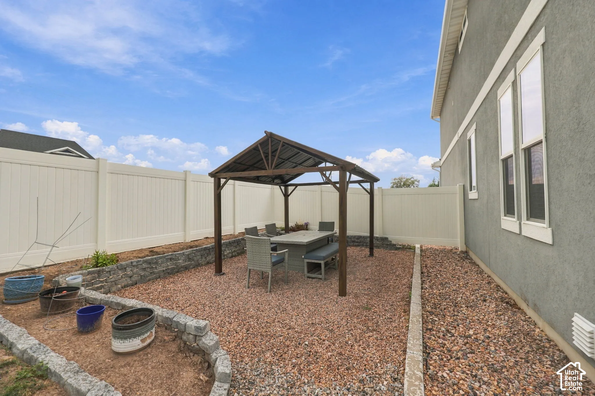 Enclosed backyard featuring a pergola, gravel ground cover, and defined planting beds