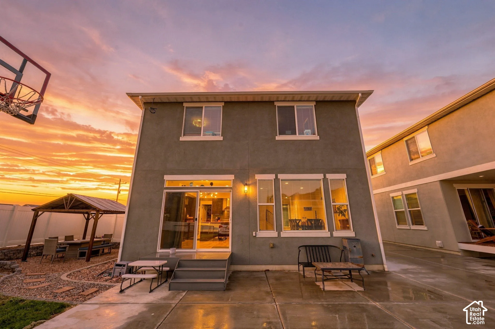 Rear exterior with multiple windows, sliding glass door, and an attached concrete patio