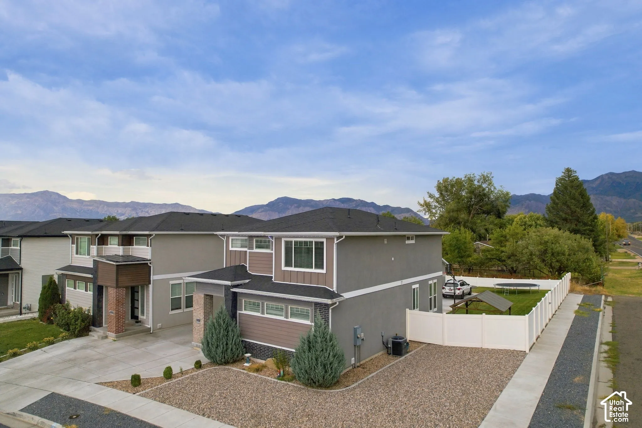Modern exterior with a combination of grey stucco and brown siding, dark shingle roof, and multiple windows