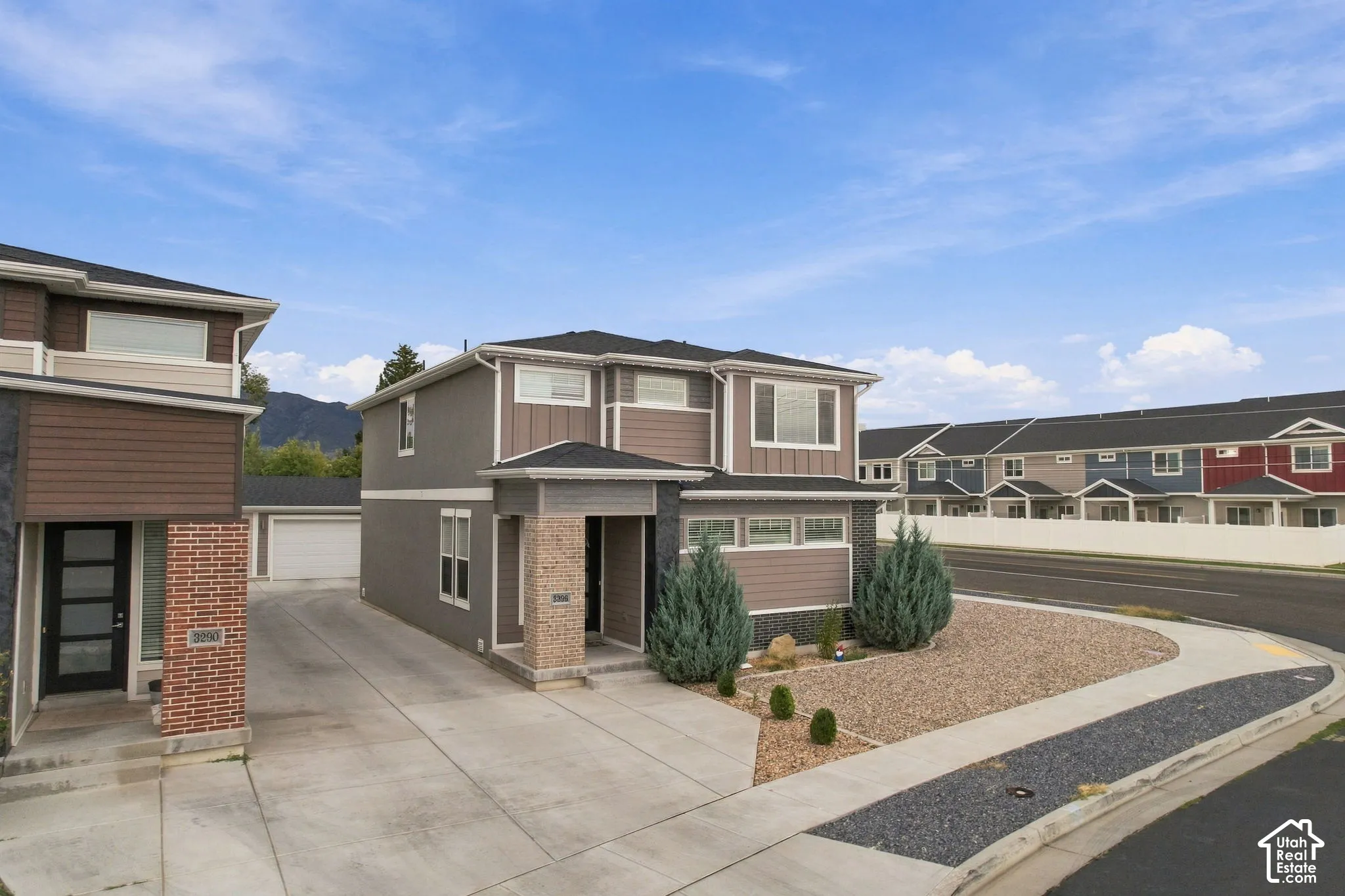 Contemporary multi-story facade featuring mixed material siding, stone accents, and a concrete driveway