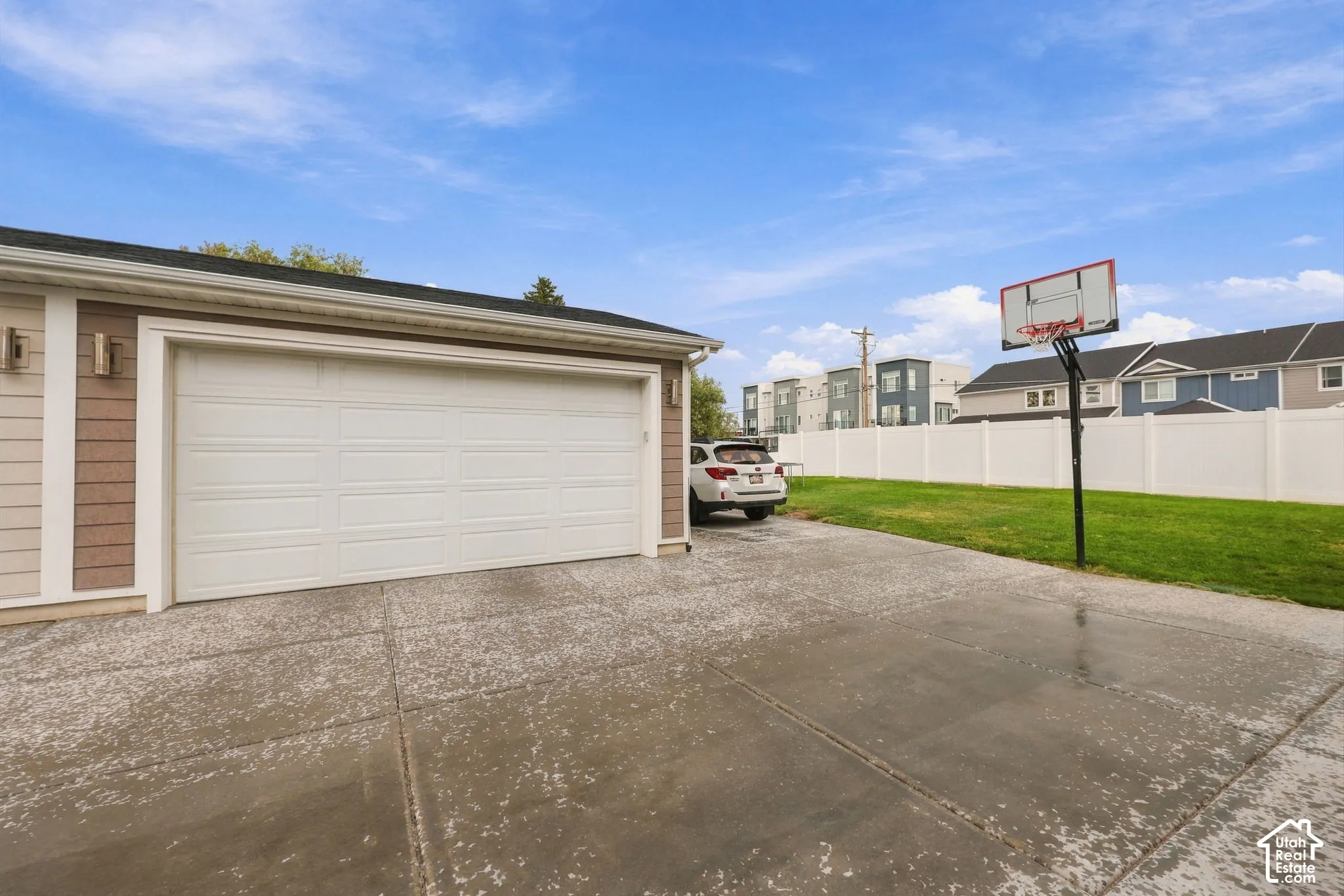 Attached two-car garage with a white panel door, concrete driveway, and exterior lighting fixtures