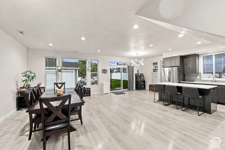 Light wood-finish flooring throughout, recessed ceiling lighting, and large windows with blinds