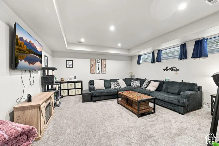 Recessed lighting, wall-mounted television, neutral carpeting, and multiple windows