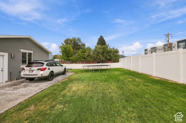 Expansive green lawn, white privacy fencing, paved driveway, and exterior wall siding