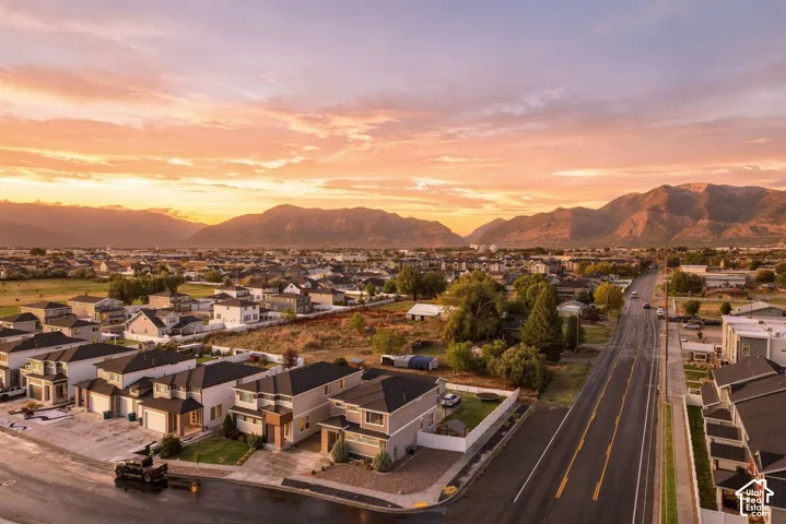 Residential area with a mountain backdrop, featuring a paved road, streetlights, and single-family homes
