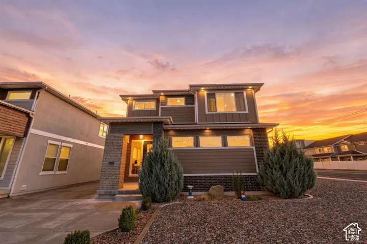 Contemporary multi-level exterior with mixed material facade, prominent entry columns, multiple window configurations, and perimeter landscaping