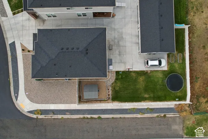 Expansive concrete driveway, gravel landscaping, asphalt shingle roofing, and a grass lawn