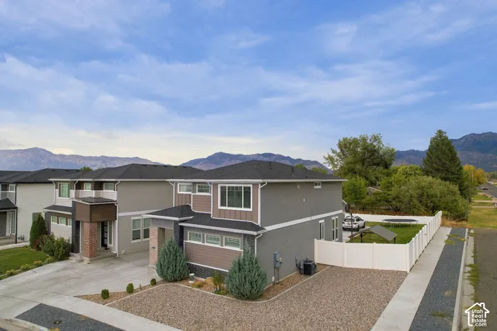 Modern exterior with a combination of grey stucco and brown siding, dark shingle roof, and multiple windows