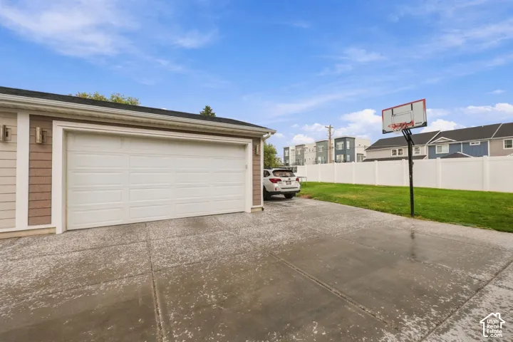 Attached two-car garage with a white panel door, concrete driveway, and exterior lighting fixtures