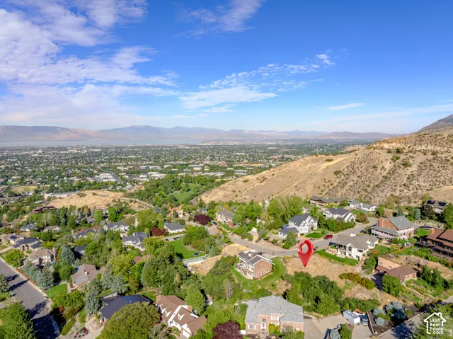 Hilly terrain with scattered mature trees and surrounding residential properties