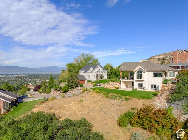Expansive property featuring a sloping landscape, multiple residential structures, and distant mountain ranges