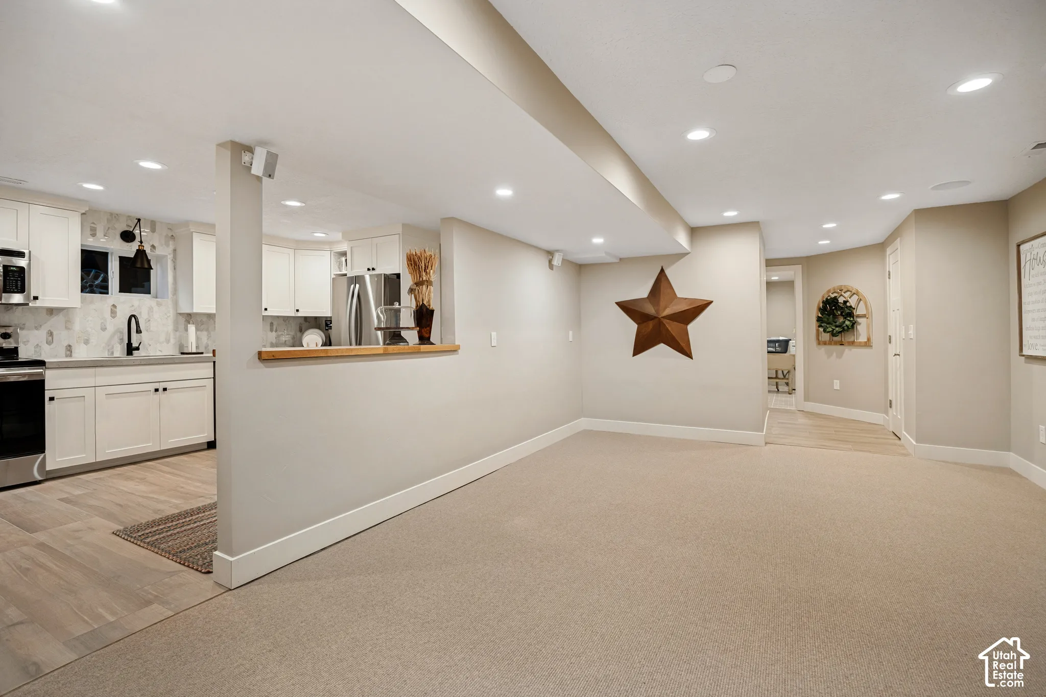 Open-concept living area with recessed lighting, light-toned carpeting, and a built-in half wall with a wood-finish countertop