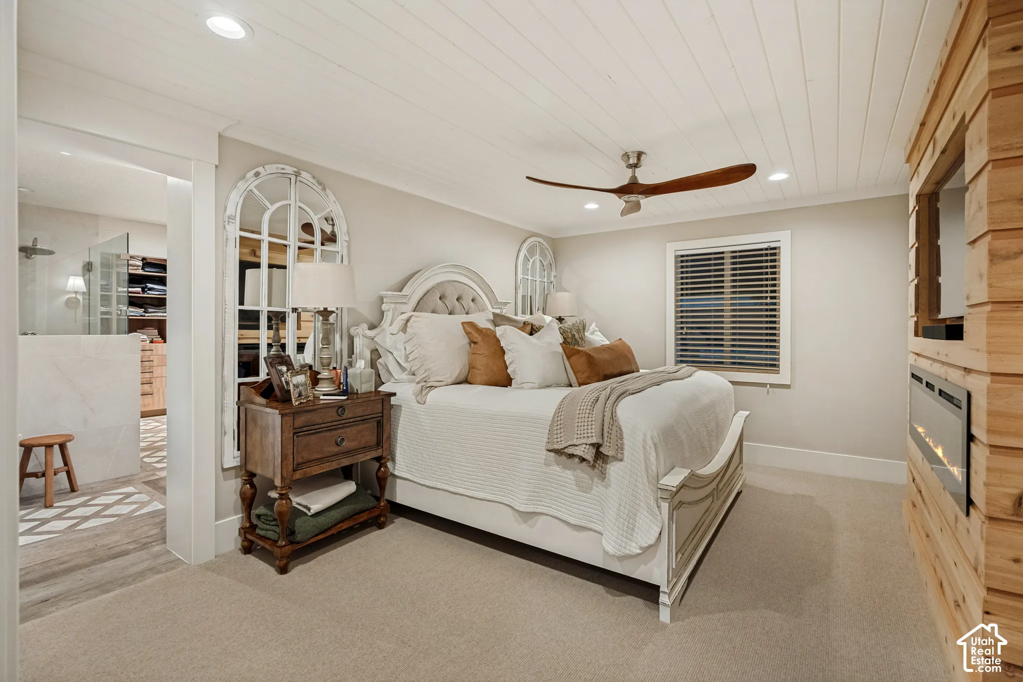 Shiplap ceiling with recessed lighting, wood-finish ceiling fan, integrated wall-mounted fireplace, window with blinds, and light-toned carpeting