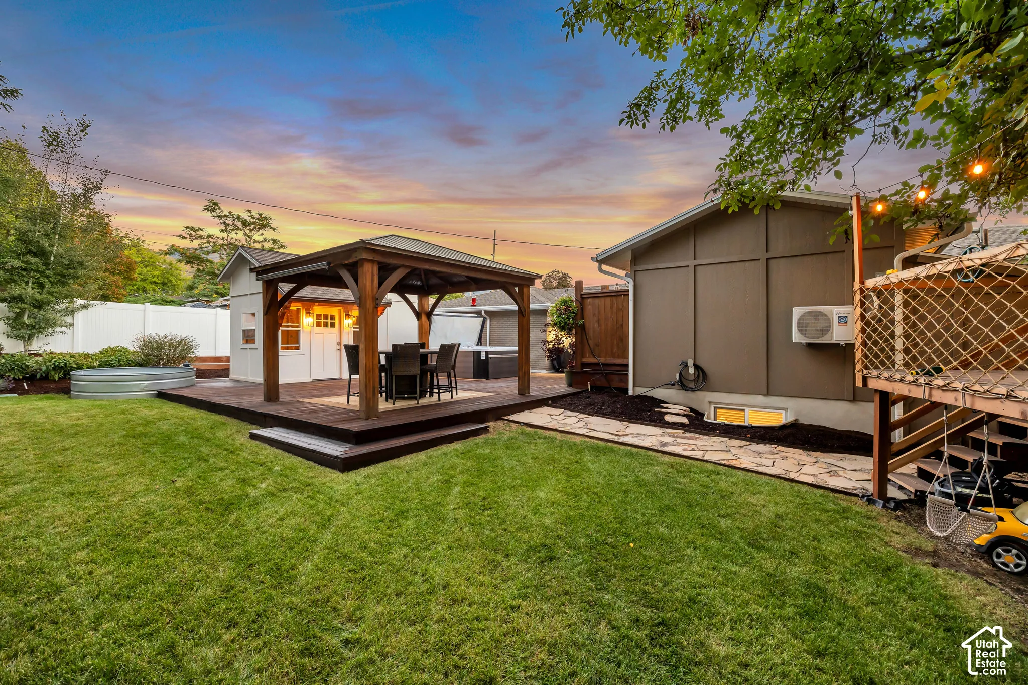 Expansive backyard featuring a manicured lawn, a raised wood deck with a pergola, a private shed, and a stone walkway