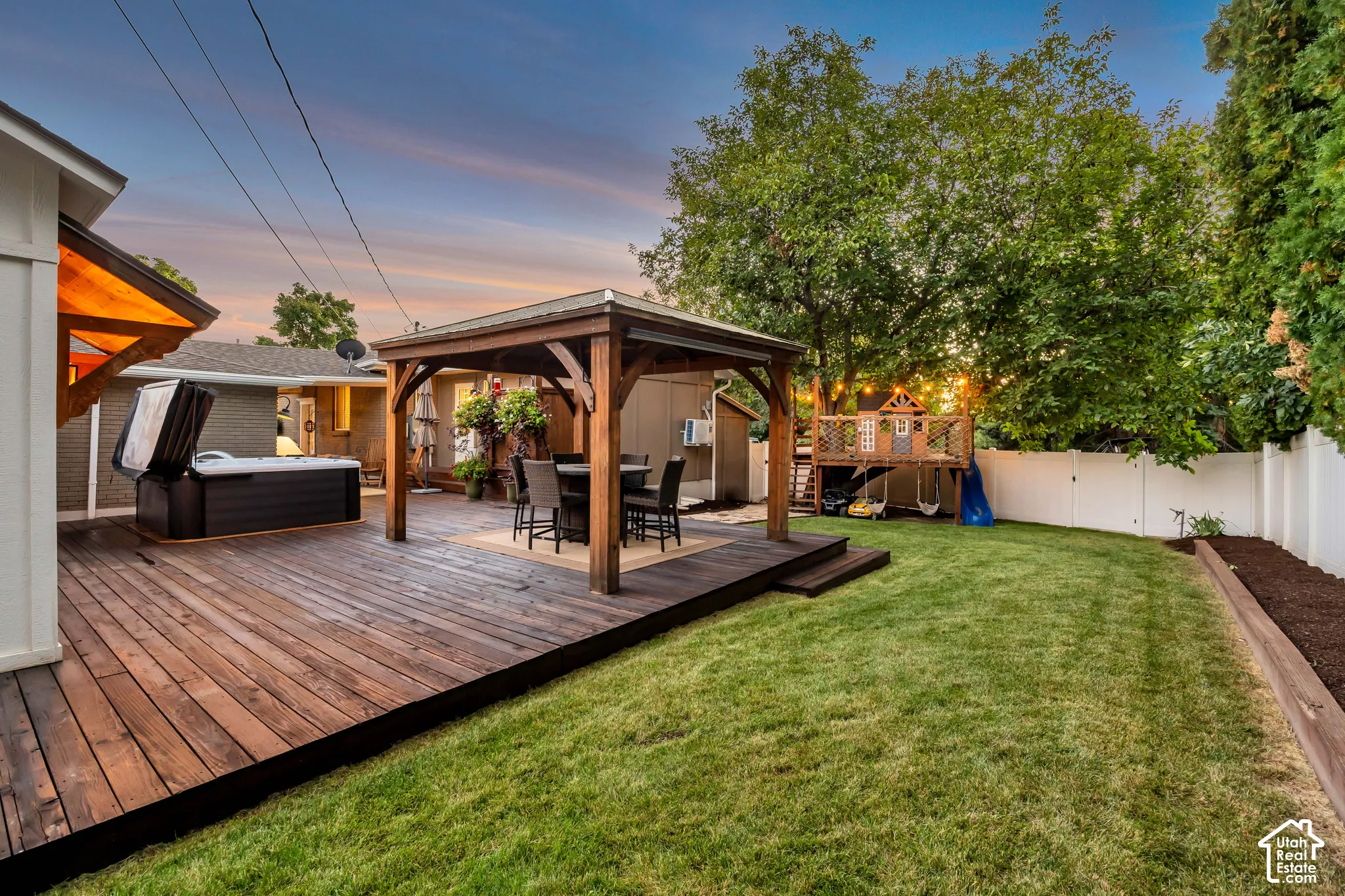 Expansive backyard featuring a wood deck, built-in hot tub, and a wood gazebo with a paved floor