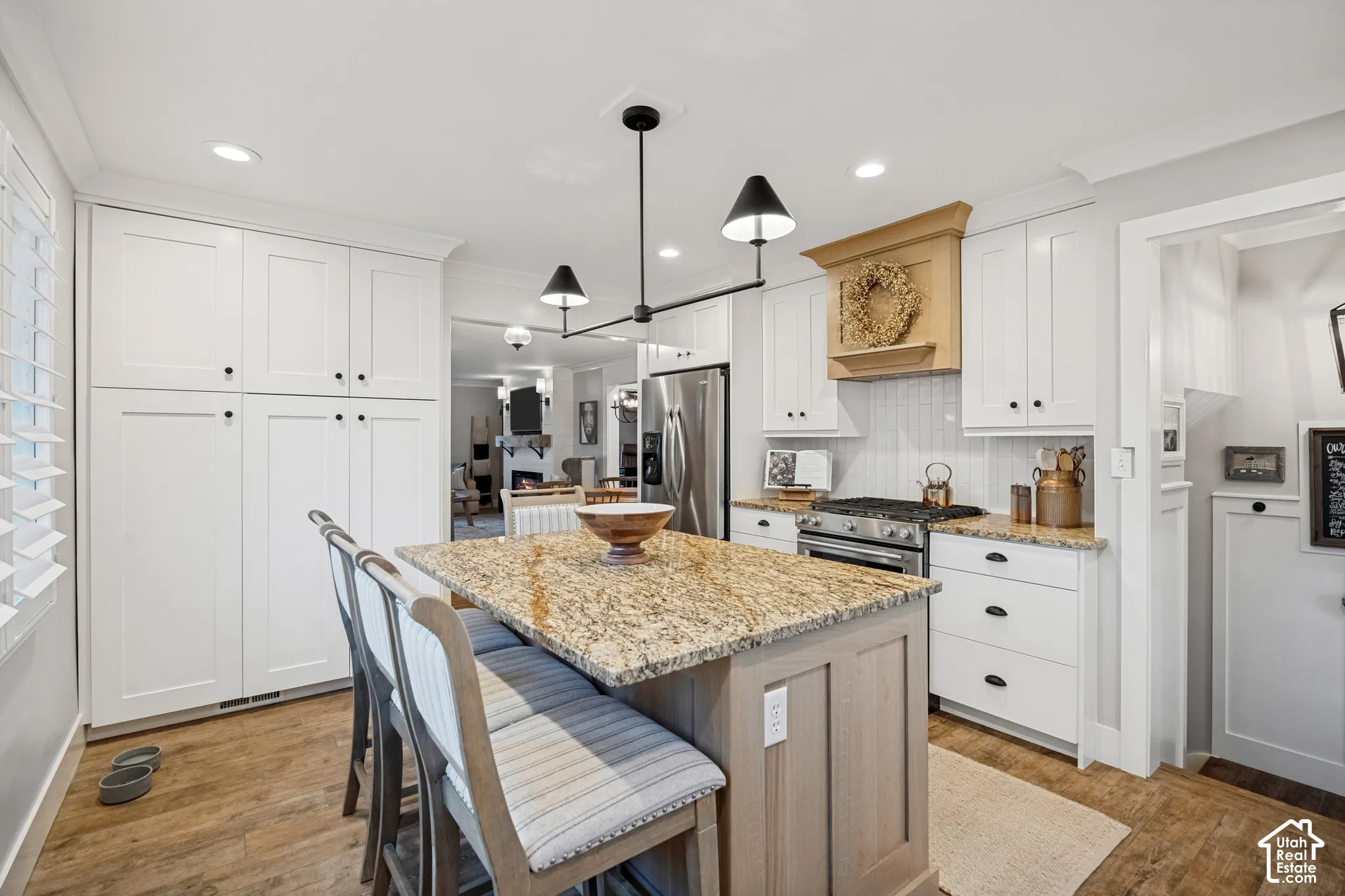 Kitchen featuring white cabinetry, a central island with a stone countertop, a built-in range, wood-finish flooring, and recessed lighting