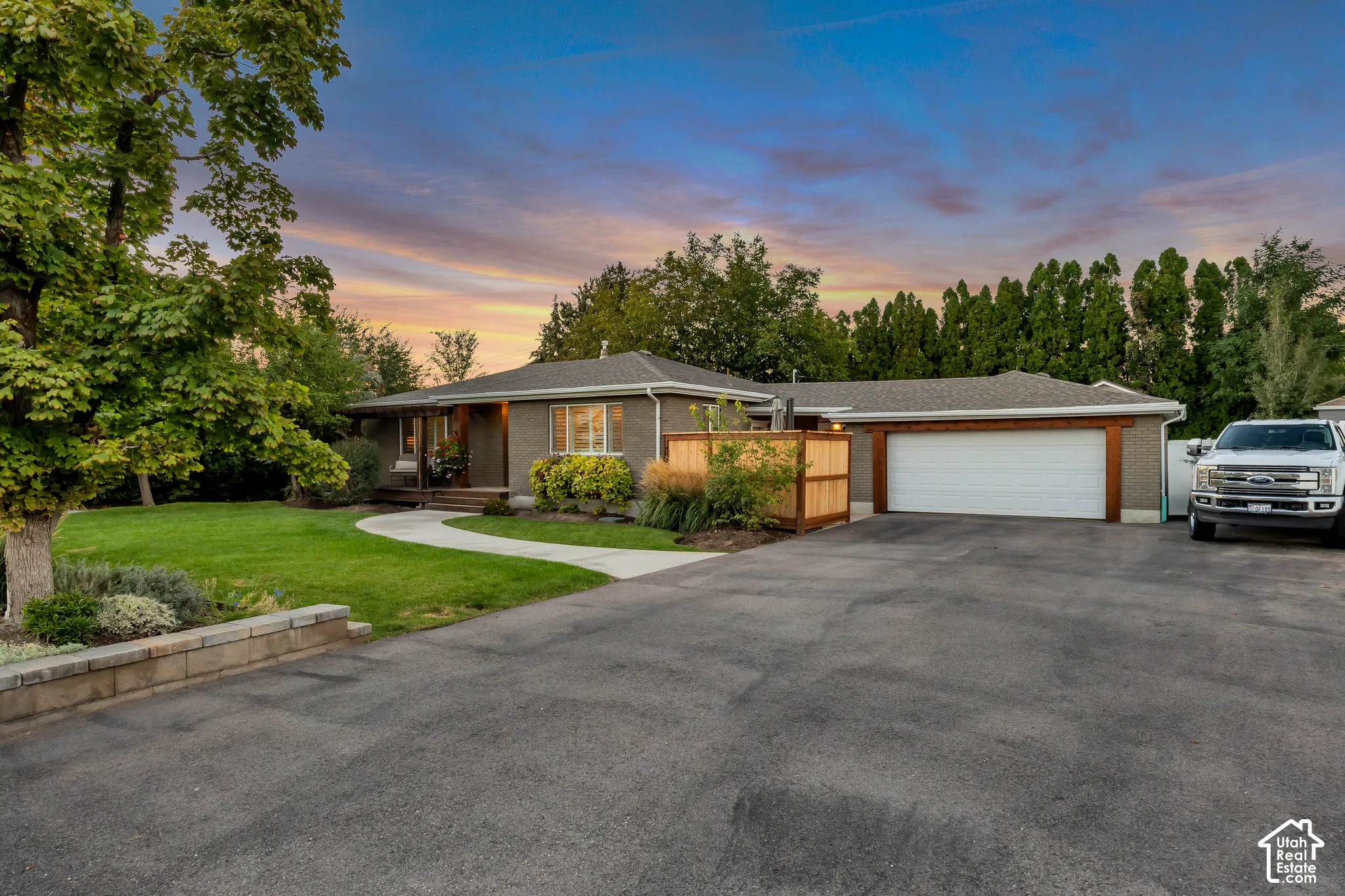 Single-story residence featuring a gray exterior and a large asphalt driveway