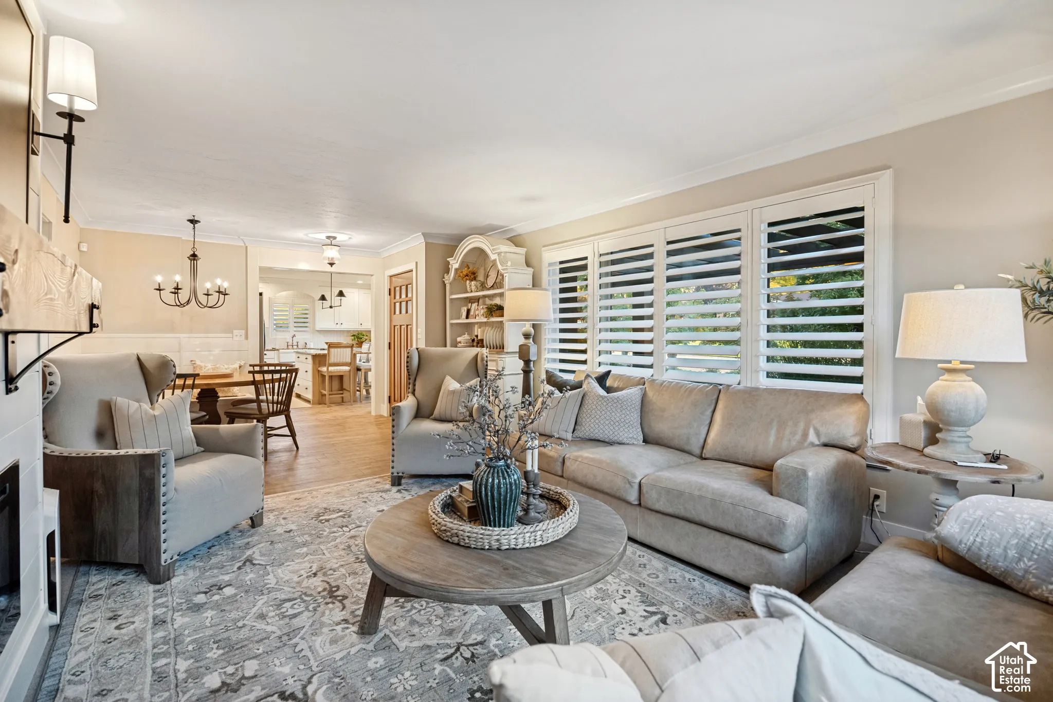 Living area with crown molding, plantation shutters, wood-finish flooring, and a decorative built-in display cabinet