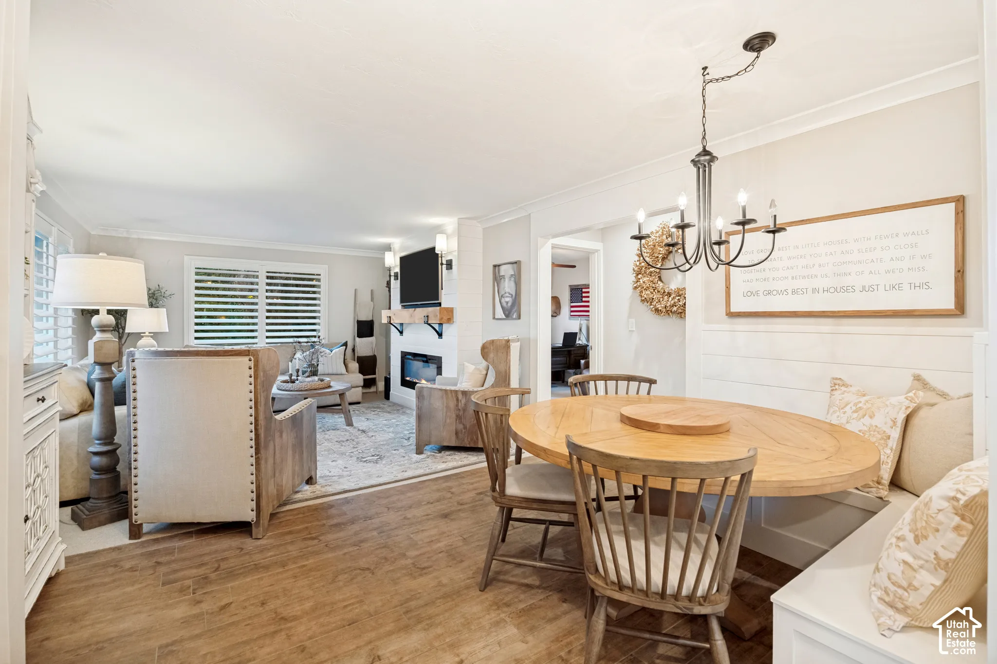 Wood-finish flooring, built-in dining bench, chandelier, fireplace, and window shutters