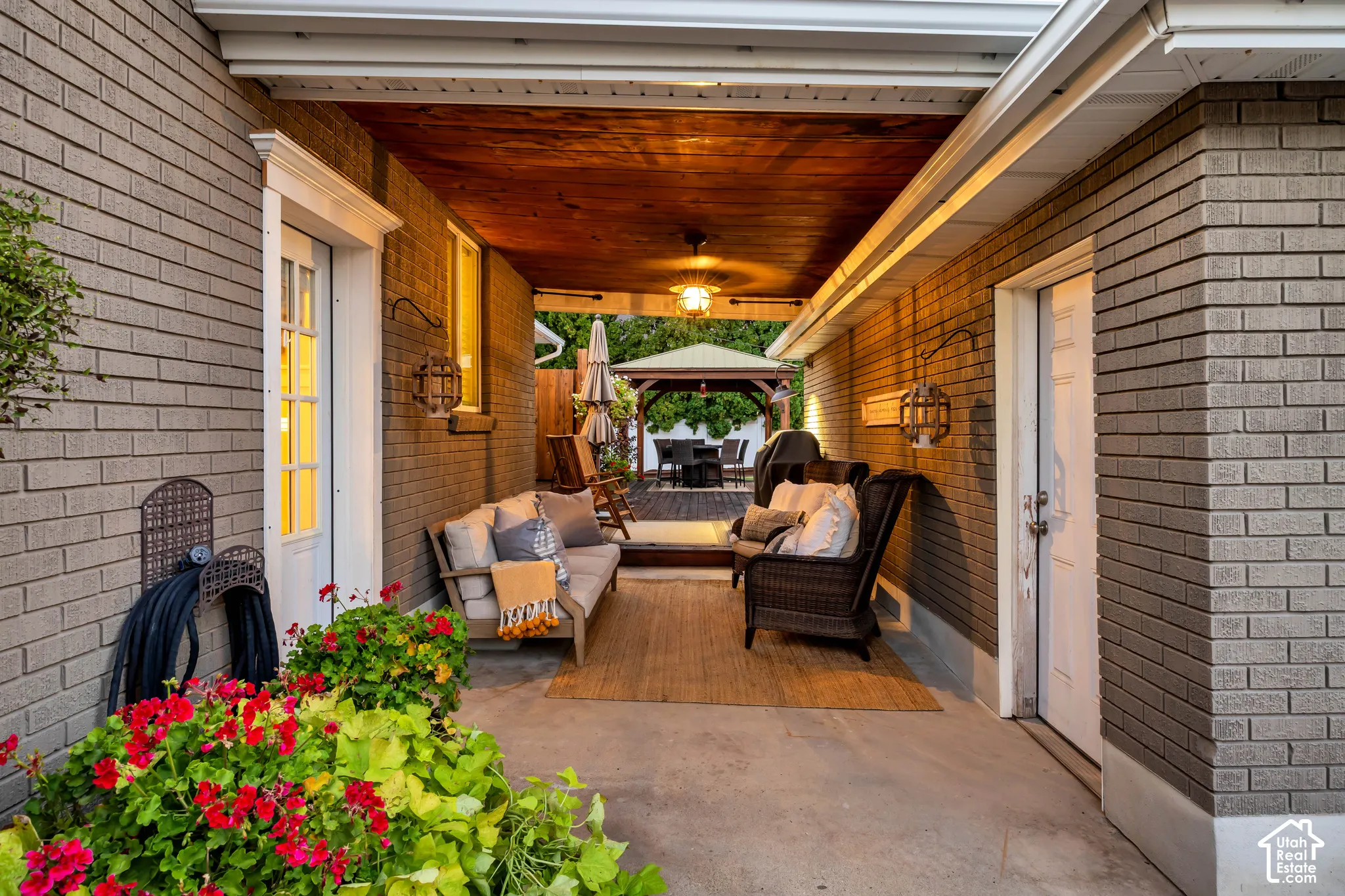 Covered patio featuring a wood-finish ceiling, mounted ceiling fan, brick exterior walls, and concrete flooring