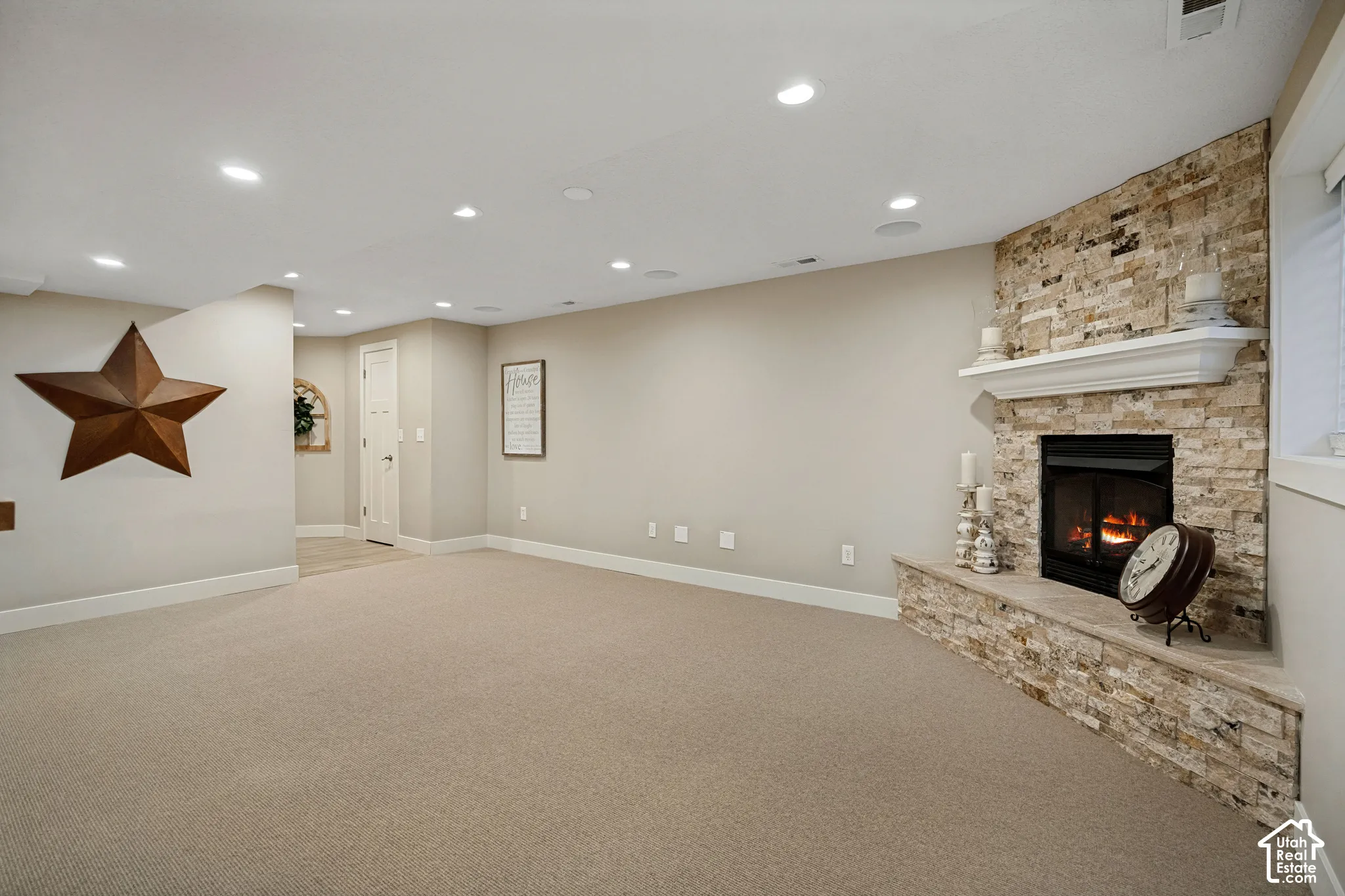 Stone veneer fireplace with an integrated mantel and hearth, recessed lighting, and carpeting
