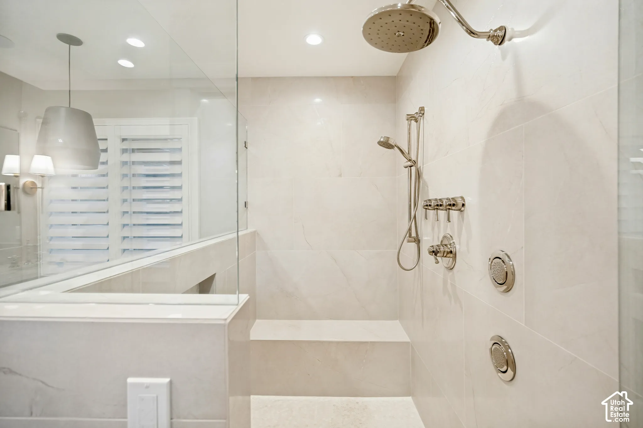 Glass-enclosed shower with a built-in bench, rain shower head, handheld shower, and body sprays