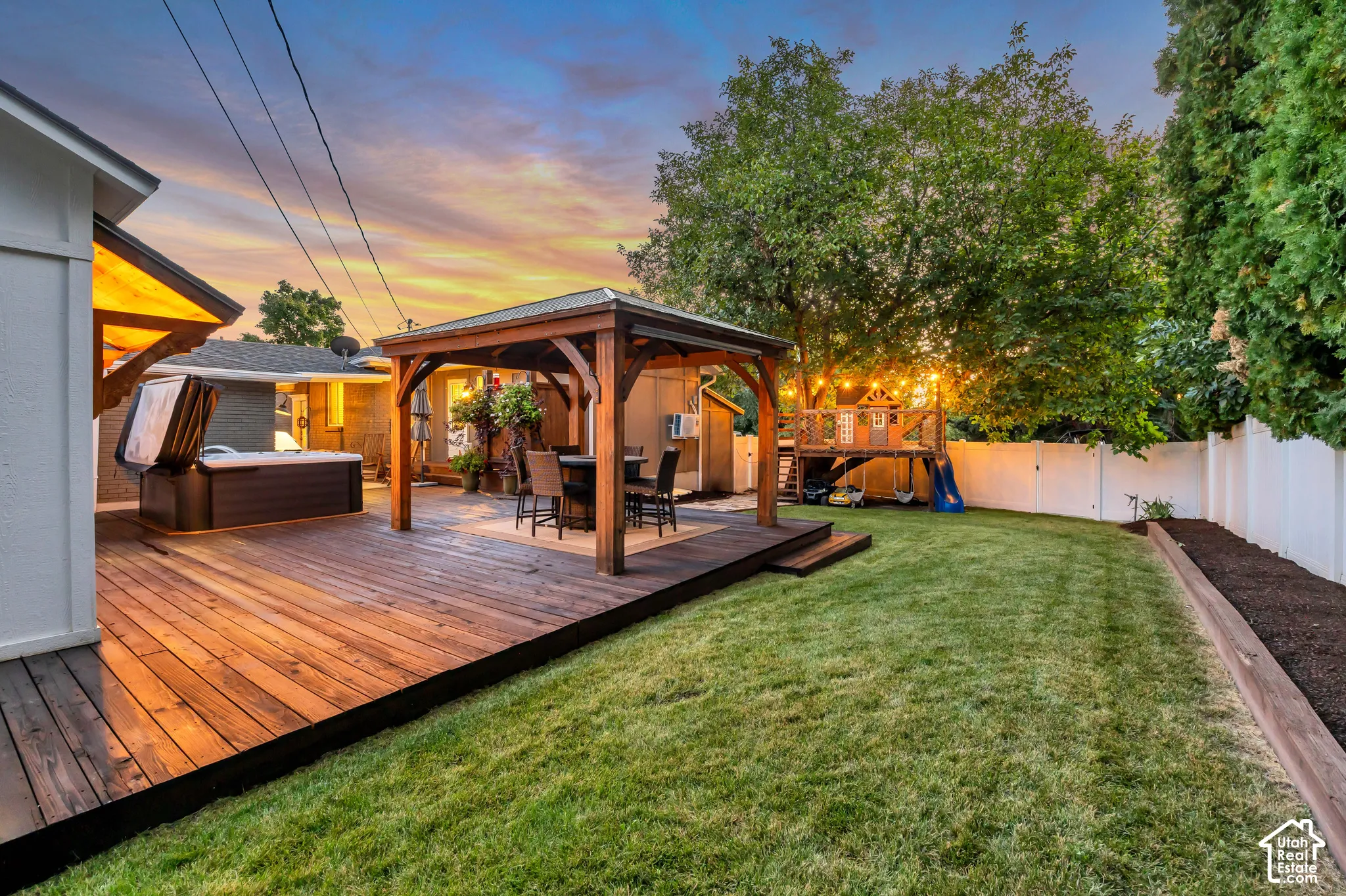 Expansive backyard featuring a wood deck, built-in hot tub, and a covered outdoor entertaining area