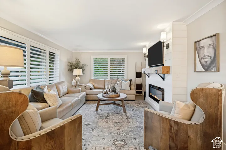 Hardwood-style flooring, white window shutters, crown molding, electric fireplace with shiplap-style surround, and wall-mounted sconces