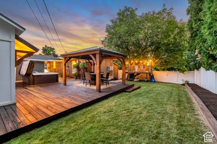 Expansive backyard featuring a wood deck, built-in hot tub, and a covered outdoor entertaining area