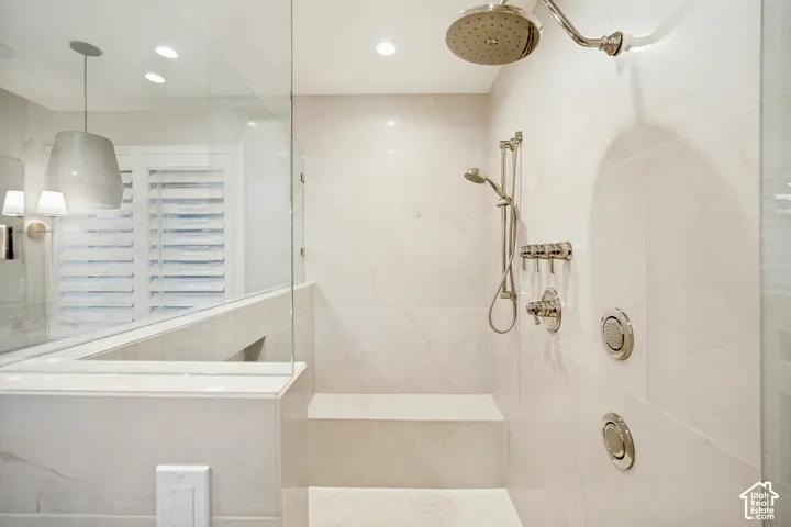 Glass-enclosed shower with a built-in bench, rain shower head, handheld shower, and body sprays