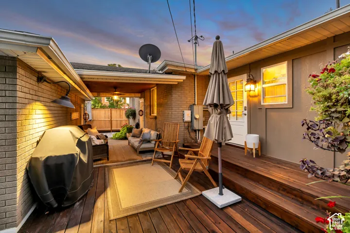 Multi-level wood-finish deck with built-in overhead lighting, brick exterior, and a privacy fence