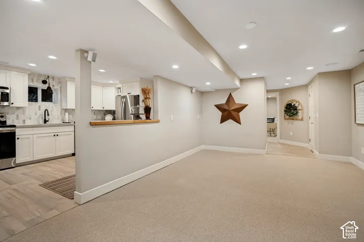 Open-concept living area with recessed lighting, light-toned carpeting, and a built-in half wall with a wood-finish countertop