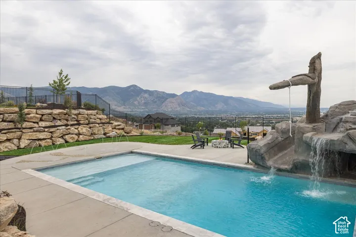 Swimming pool with integrated steps, rock-feature waterfall, and concrete decking